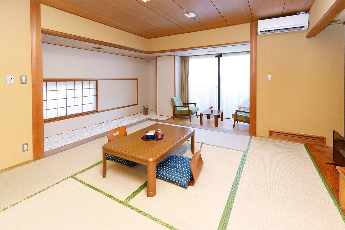A traditional Japanese room with tatami flooring, a low wooden table, and a sliding door leading to a balcony.