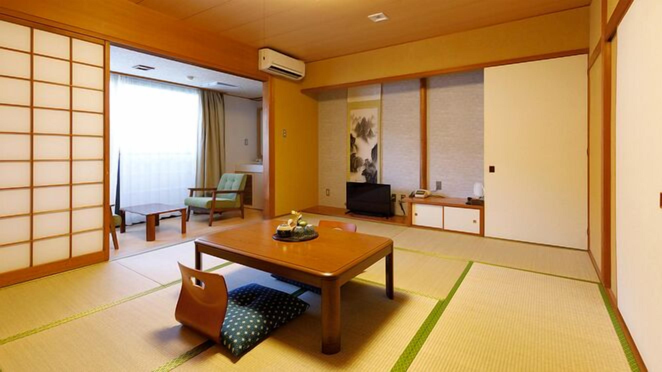 A traditional Japanese-style room with tatami flooring, a low table, a sofa, and a television.
