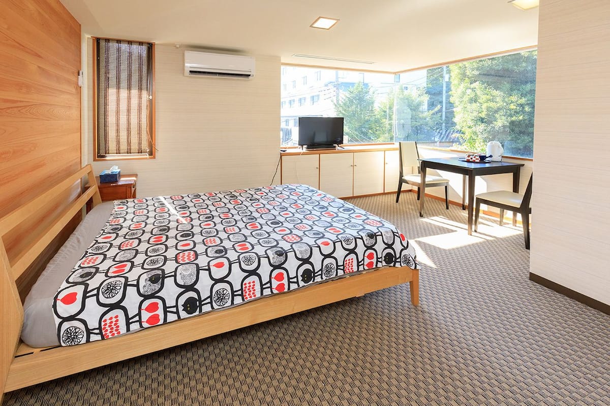 A hotel room with a bed, a desk, a chair, and a TV.
