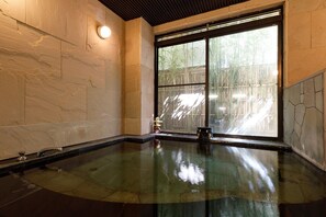 A spa room with a large glass window, a stone wall, and a wooden ceiling. - Miyabitake (Yugawara)