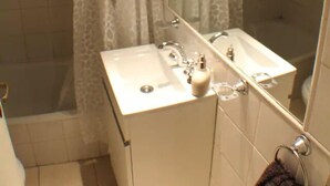 Un bagno con doccia, due lavandini e uno specchio grande.
