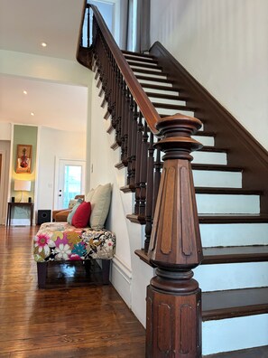A wooden staircase with a handrail, leading to a landing with a cushioned bench.