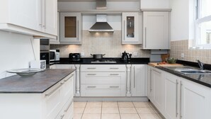 Une cuisine moderne avec des meubles blancs, un plan de travail noir et une hotte en acier inoxydable.