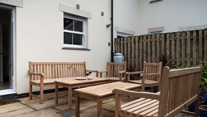 Une terrasse dotée de mobilier en bois, notamment de bancs et d’une table, ainsi que d’une plante en pot.
