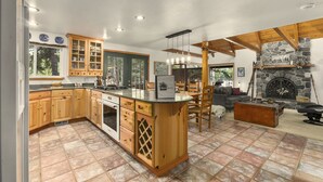 Une cuisine spacieuse avec des meubles en bois, un îlot central et une cheminée en pierre.