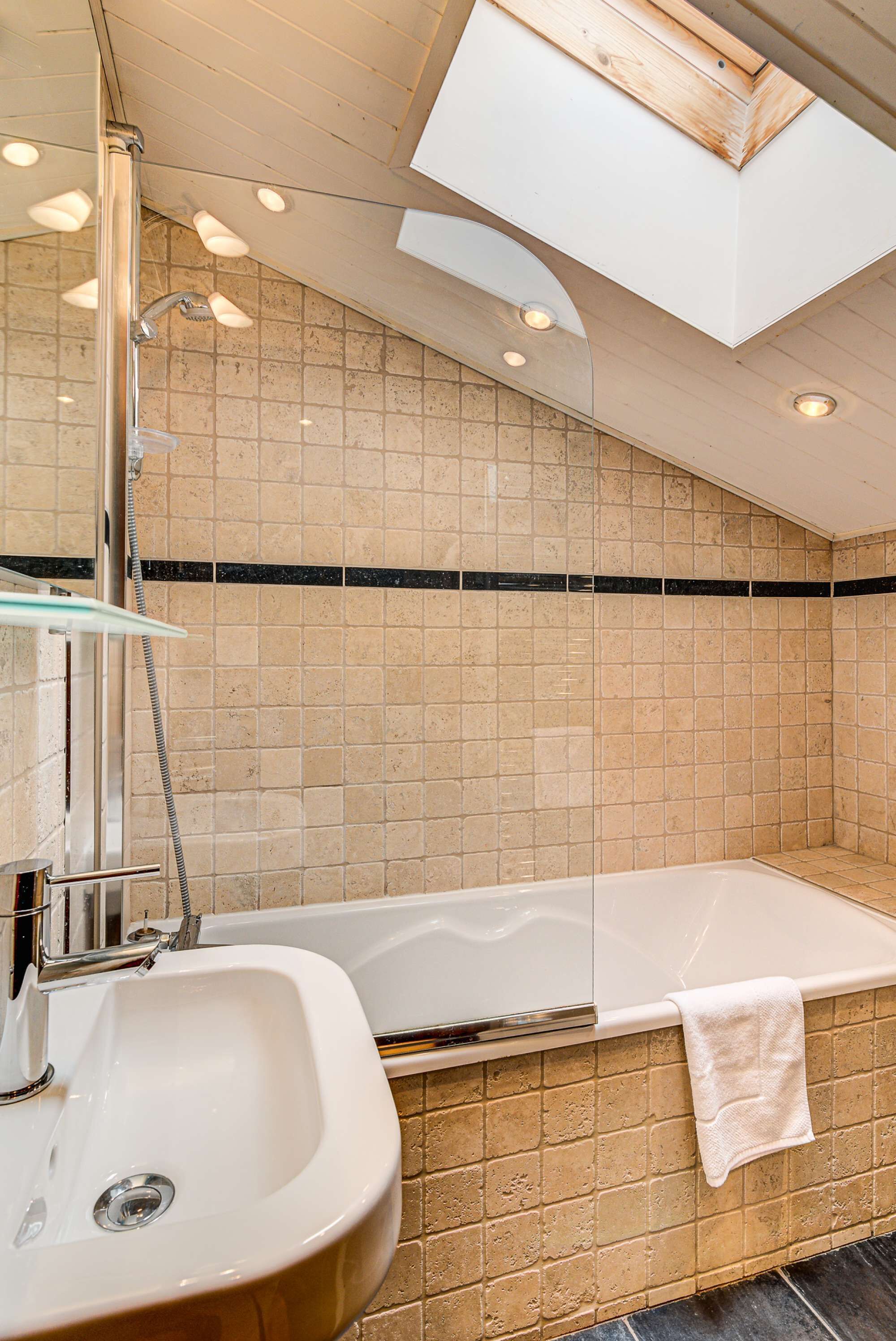 A modern bathroom with a glass-enclosed shower, a white sink, and a bathtub.
