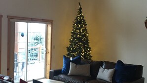 Een woonkamer met een kerstboom, leren banken, een salontafel en een kamerbreed tapijt met een patroon.