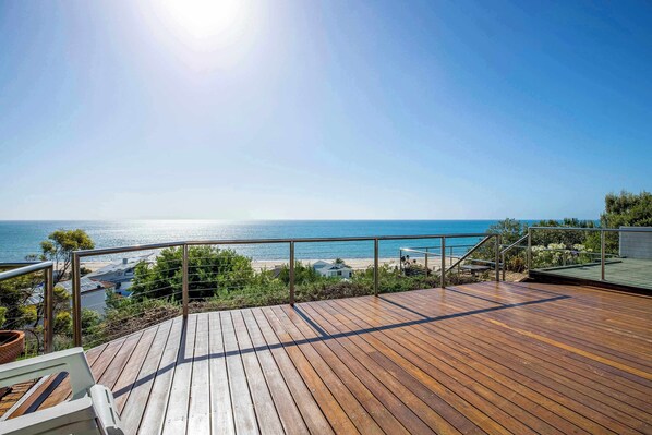 A wooden deck with a metal railing overlooking a beach.