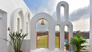 Um edifício branco com arcadas e um sino.