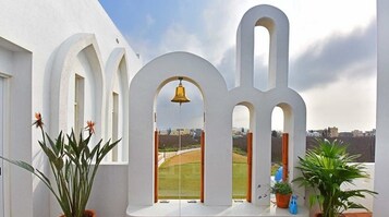 Un edificio blanco con arcos y una campana.