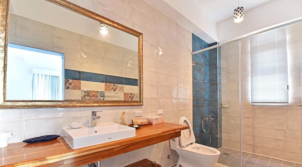 A modern bathroom with a wooden vanity, a large mirror, a shower enclosure, and a toilet.