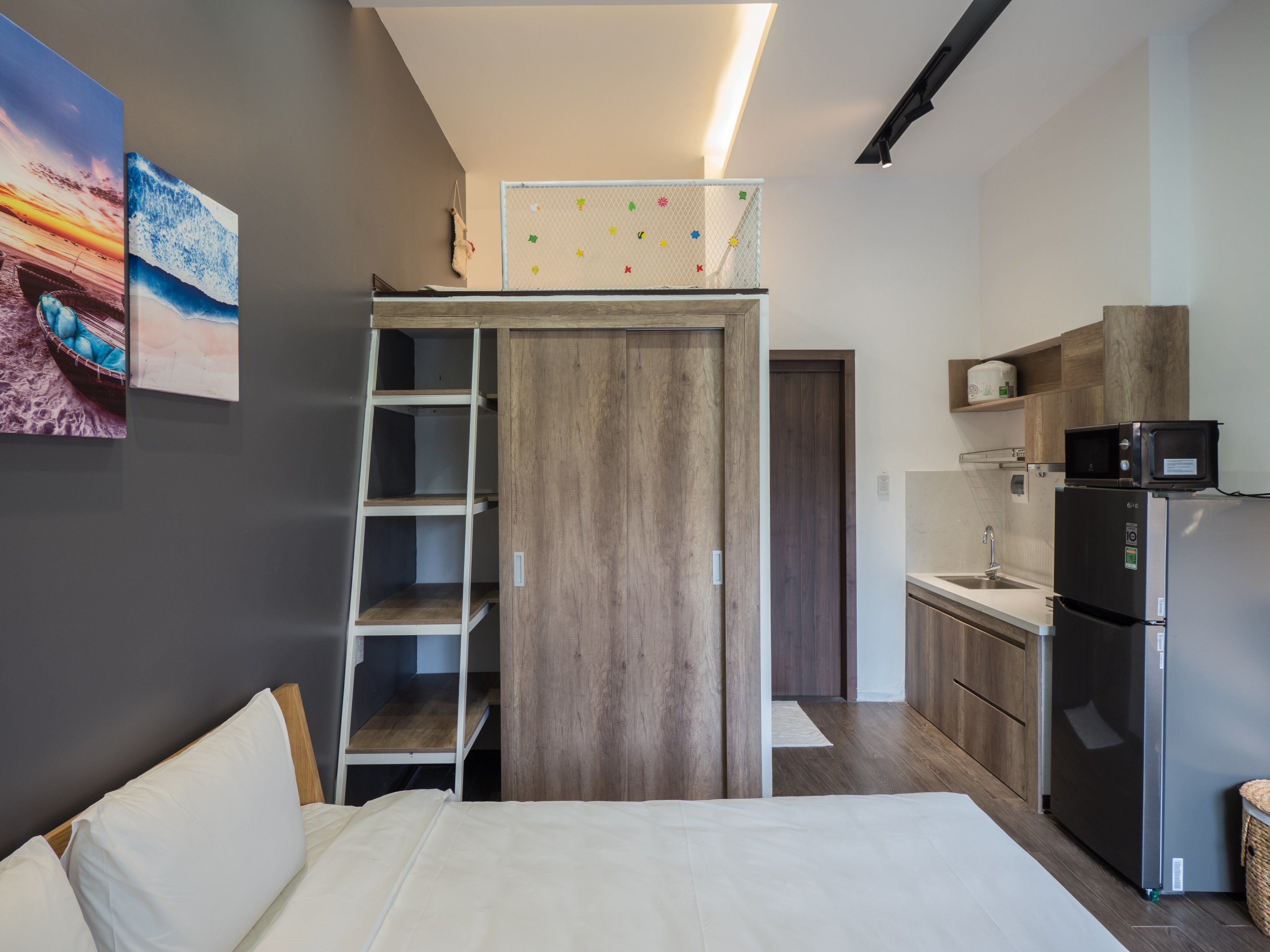 A compact bedroom with a bunk bed, a kitchenette with a microwave and refrigerator, and a small bathroom.