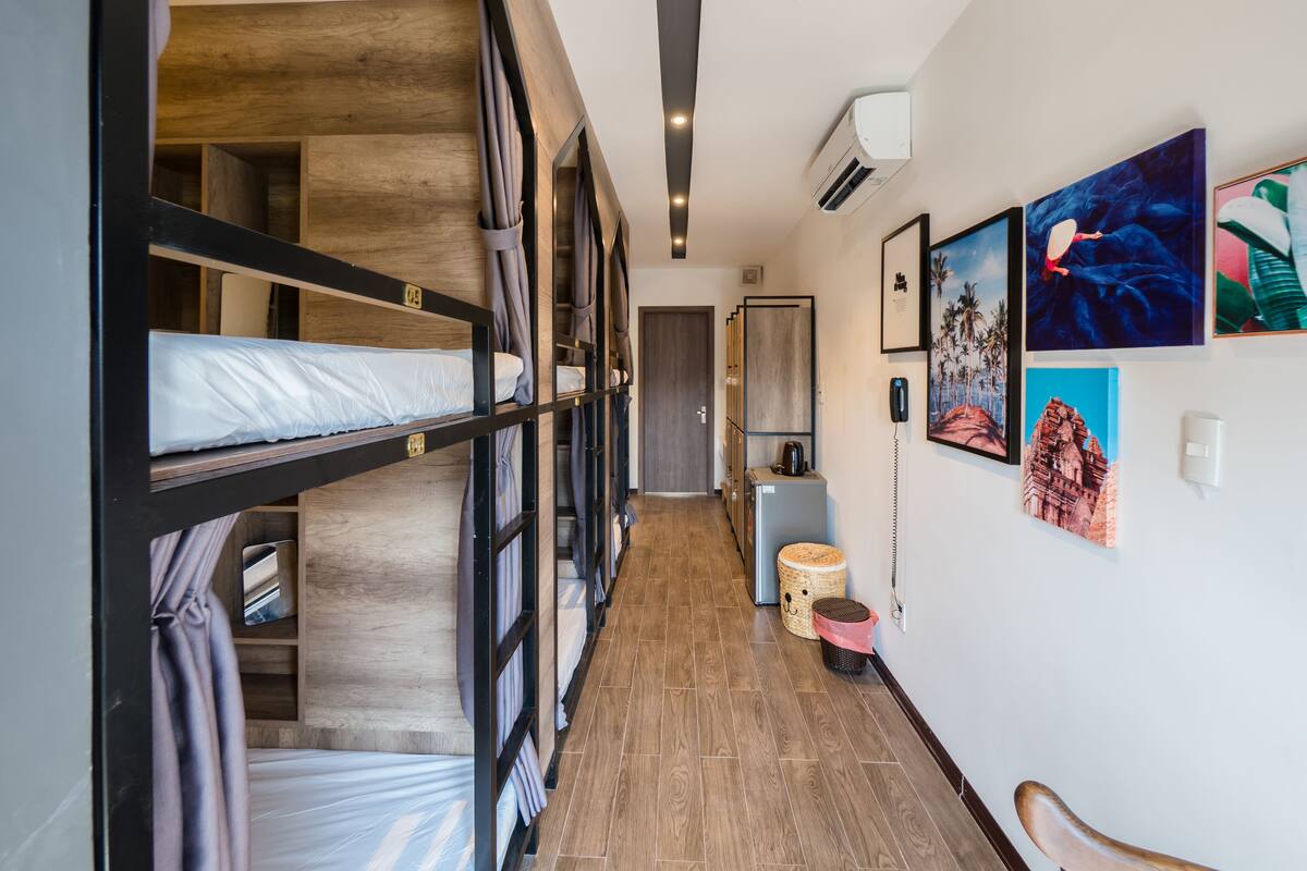 A hotel room with bunk beds, a wooden floor, a small seating area, and artwork on the walls.