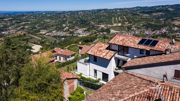 Paisagem rural com vinhedos em socalcos e edifícios tradicionais com telhados de barro vermelho.