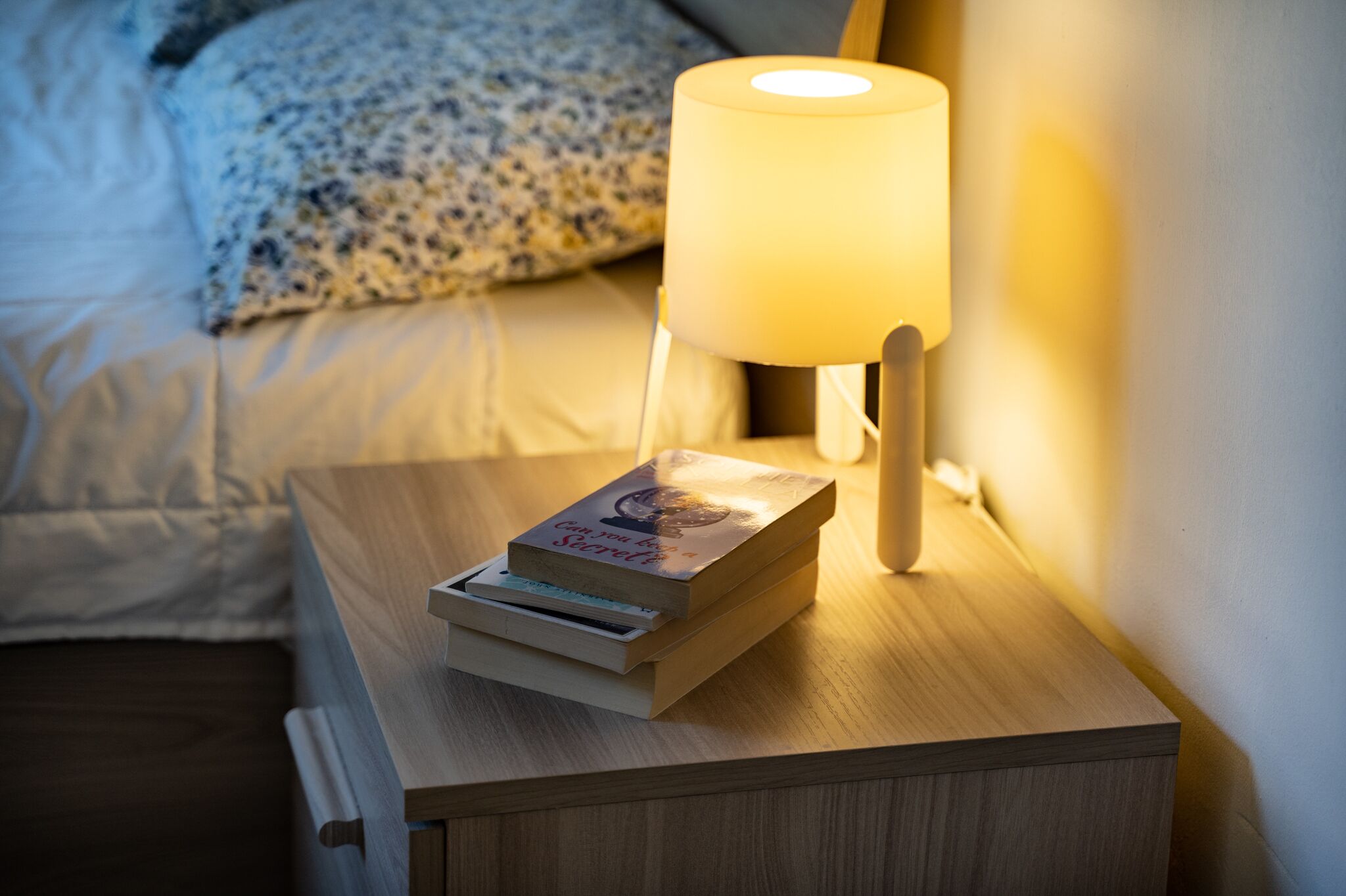 A bedside table with a lamp and a book.
