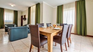Un comedor con una mesa de madera, cuatro sillas y un sofá.