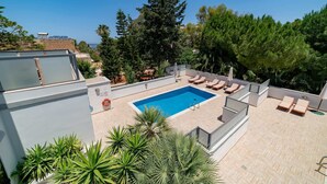 Una piscina en la azotea con sillones de descanso y vistas despejadas al mar.