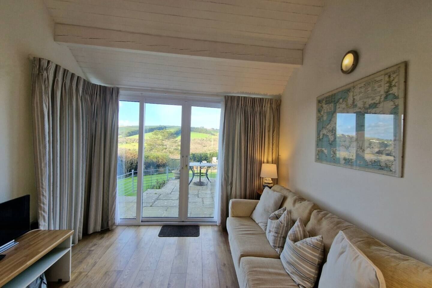 Una sala de estar con un sofá, un televisor y vistas a un paisaje a través de un ventanal.