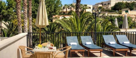 A poolside area with lounge chairs, a table with flowers, and palm trees.