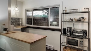 Une cuisine moderne dotée d’un plan de travail en bois, d’un four encastré, d’un four à micro-ondes, d’une machine à café et d’une étagère contenant des ustensiles de cuisine.