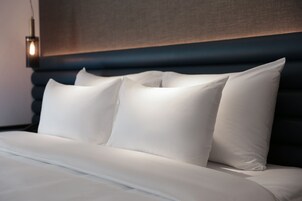 A neatly made bed with white linens and a dark headboard.