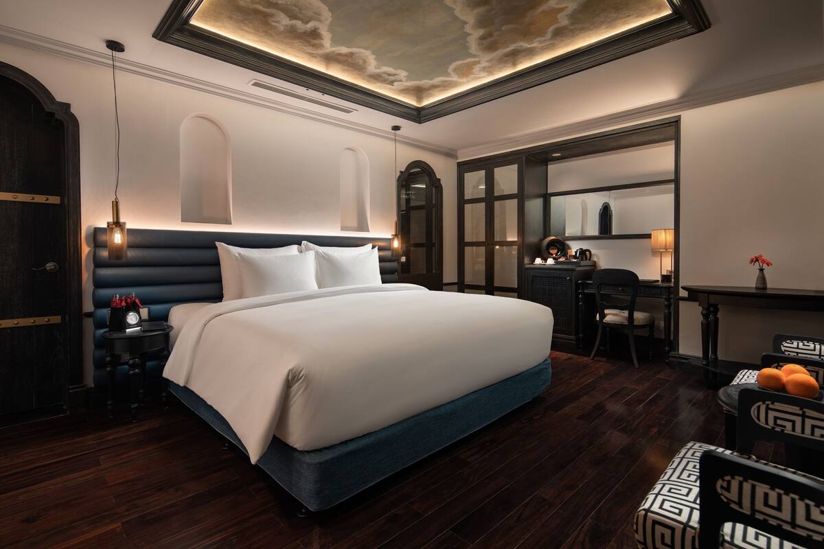 Una habitación de hotel moderna con una cama grande, un escritorio y una silla.