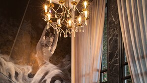 A grand piano in a room with a large mural, a chandelier, and curtains. - La Sinfonía del Rey Hotel & Spa (Hanoi)