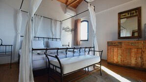 A four-poster bed with white linens, a wooden headboard, and a canopy. A wooden dresser with a mirror is to the right. - Villa Shanti | Pool, Beach & Basketball court (Rt Veslo)
