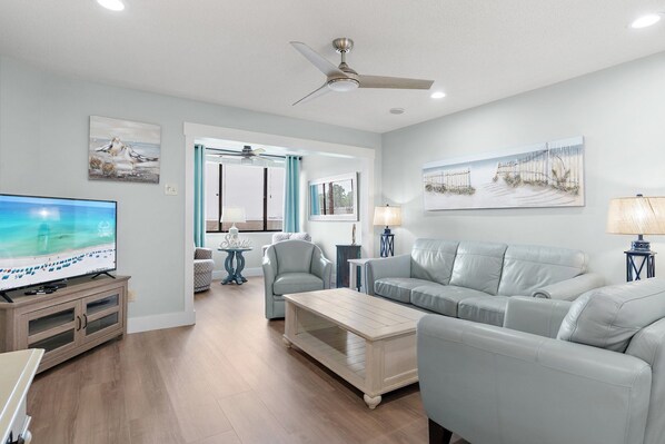 A living room with a television, sofa, coffee table, and artwork on the walls.