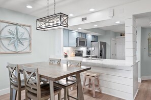 A modern kitchen with a central island, stainless steel appliances, and a hanging light fixture. - "Salty Sun" - Golf Cart (included), Tennis, Pools, Golf, Beach... it's all here! (Destin)