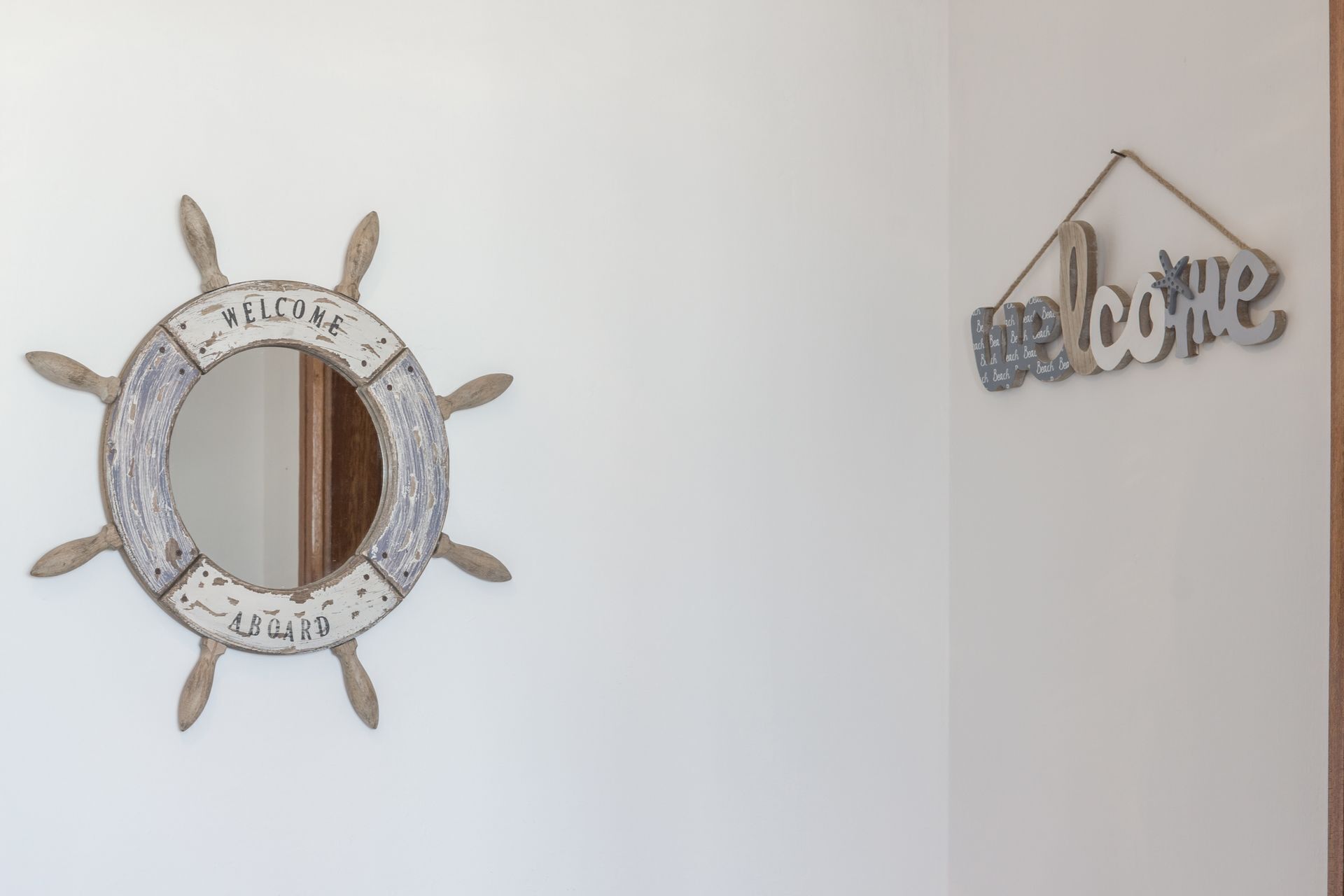 A wall with a circular mirror and a 'Welcome' sign.