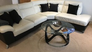 A modern living room with a white sectional sofa, black cushions, and a glass coffee table. - Toothbrush Apartments - Ipswich Waterfront - Regatta Quay (Ipswich)