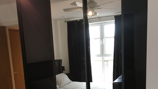 A bedroom with a bed, a desk, a chair, a wardrobe, and a ceiling fan. - Toothbrush Apartments - Ipswich Waterfront - Regatta Quay (Ipswich)