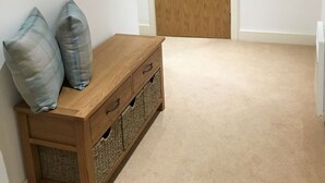 A hallway with a wooden bench, two pillows, and a closed wooden door. - Toothbrush Apartments - Ipswich Waterfront - Regatta Quay (Ipswich)