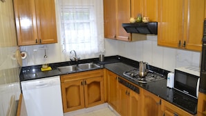 Una cocina con armarios de madera, lavavajillas, estufa y microondas.