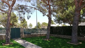 Un jardín ajardinado con un sendero pavimentado, setos verdes y árboles.