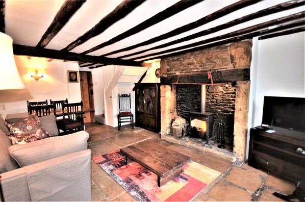 Cozy living room with a stone fireplace, comfortable seating, and a mounted television.