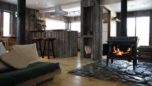 Un salon chaleureux avec une cheminée en pierre, un canapé vert et un coin bar en bois.