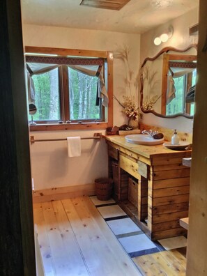 A wooden bathroom with a large window, a sink, and a mirror. - Chalet Romantique (Sutton)