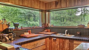 Une cuisine rustique avec des meubles en bois, une grande fenêtre et une vue sur les arbres.