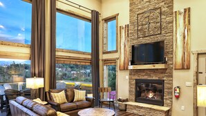 A spacious living room with a fireplace, large windows, and a stone accent wall.
