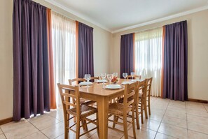 Ein Esszimmer mit einem Holztisch, gedeckt für sechs Personen, umgeben von Stühlen.