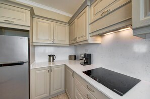 Eine Küche mit hellen Schränken, einem Edelstahlkühlschrank, einer Bosch-Induktionskochplatte und einer Kaffeemaschine.