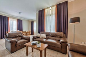 Ein Wohnzimmer mit zwei braunen Ledersofas, einem Holztisch und einer Stehlampe.