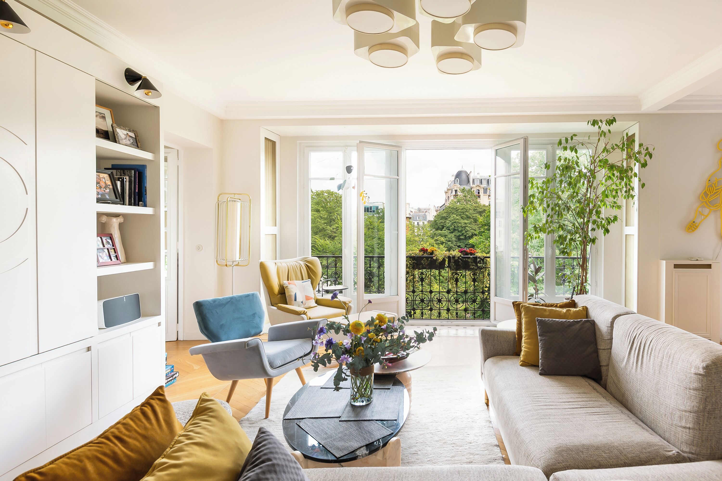 A modern living room with a sofa, armchairs, a coffee table, and a bookshelf.