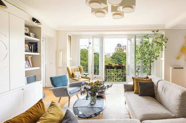 A modern living room with a sofa, armchairs, a coffee table, and a bookshelf.