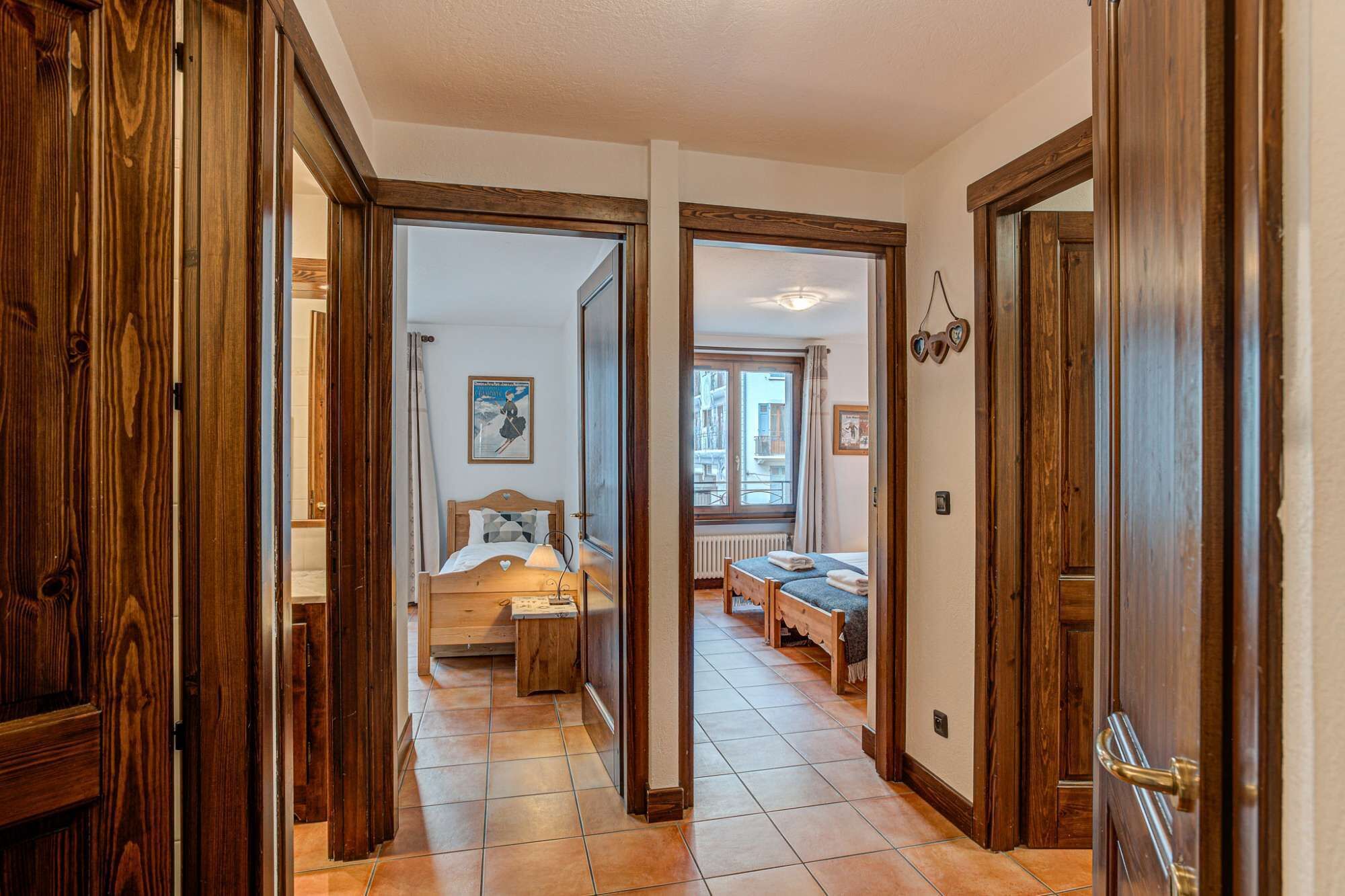 Pasillo que lleva a un dormitorio con cama, mesita de noche y ventana.