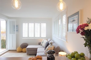 A living room with a grey sofa, a coffee table with croissants, a vase with flowers, and a bowl of green apples. - Jack's Stay, stylish apartment, Salcombe, parking (Salcombe)