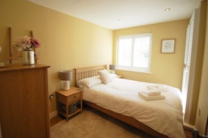 A bedroom with a bed, bedside tables, a window, and a wall decoration.