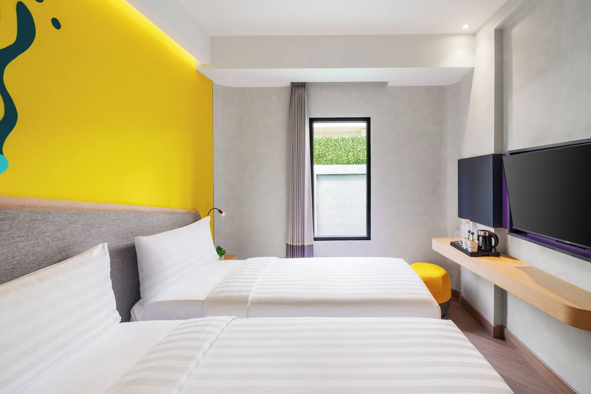 Una habitació d'hotel moderna amb un llit gran, una televisió i una taula petita amb una cafetera.